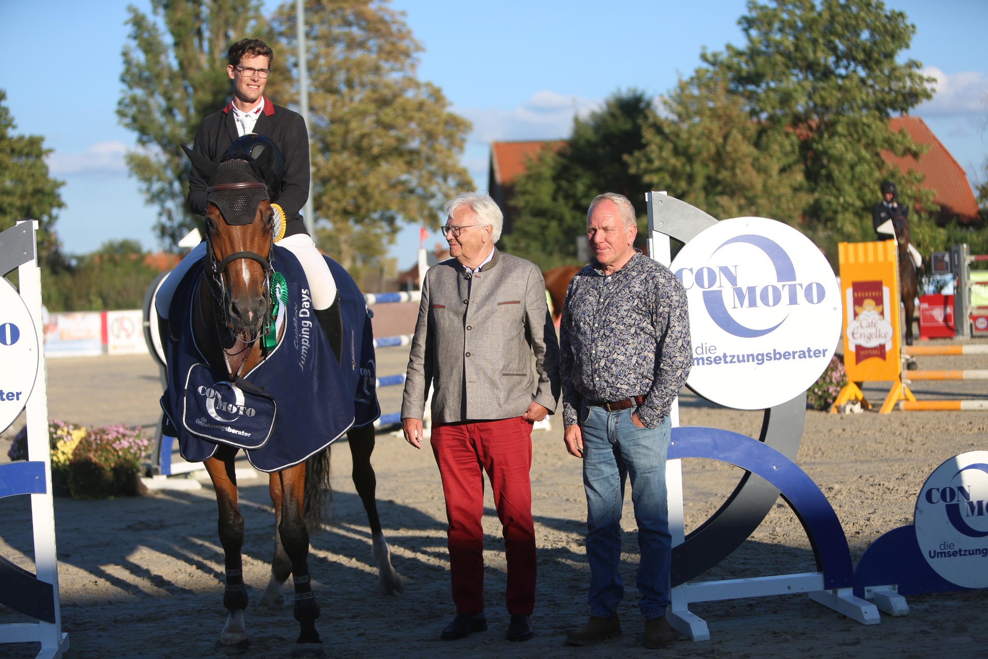 Harm Lahde, Sieger des Großen Preises bei den ConMoto Jumping Days, auf Henora. Es gratulieren ConMoto-Geschäftsführer Ralf Feierabend und der Harsumer Tunierchef Franz Bormann